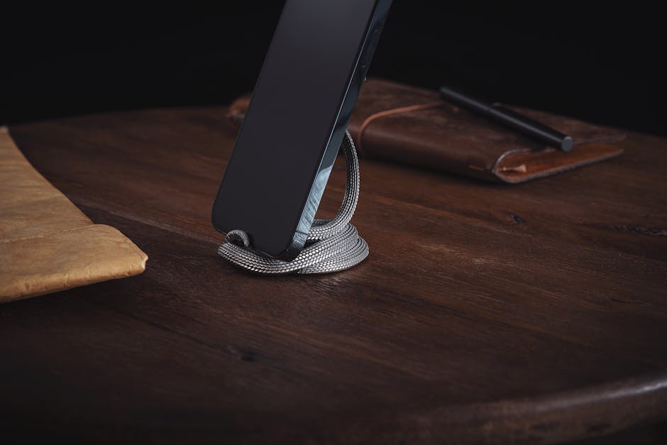 A sleek smartphone propped up by a snake figurine on a wooden desk. Sophisticated and modern.