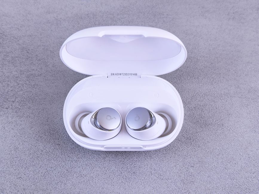 High-quality white wireless earbuds displayed in an open charging case on a textured surface.