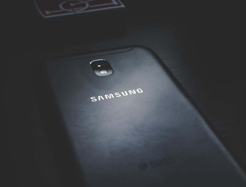 Detailed view of a smartphone on a dark wooden surface highlighting its logo.