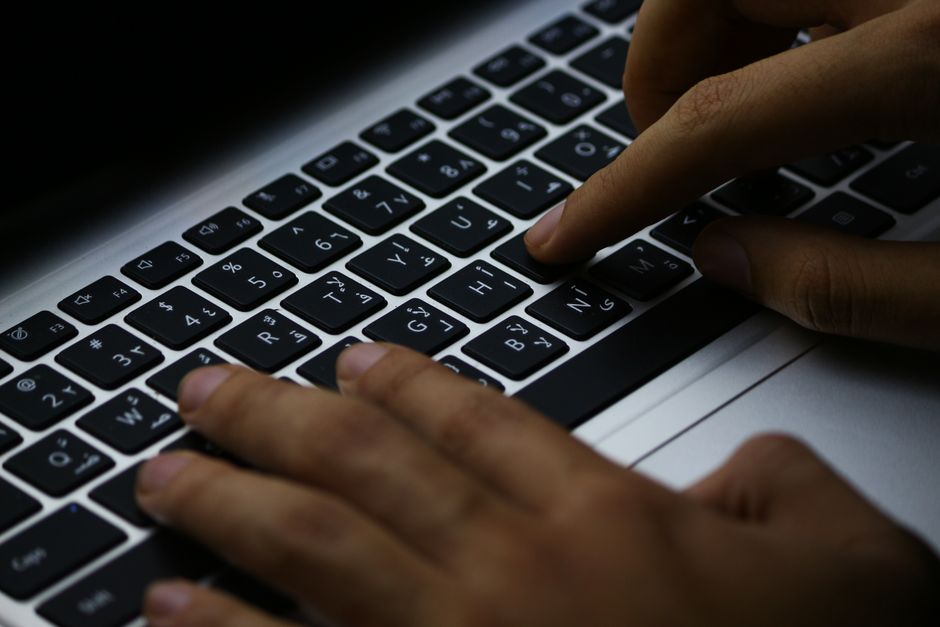 Focused typing on a laptop's illuminated keyboard, enhancing productivity in a digital workspace.