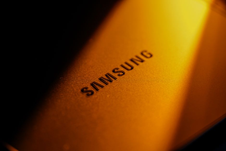 Dramatic close-up of a Samsung electronic device highlighted by golden lighting and shadows.