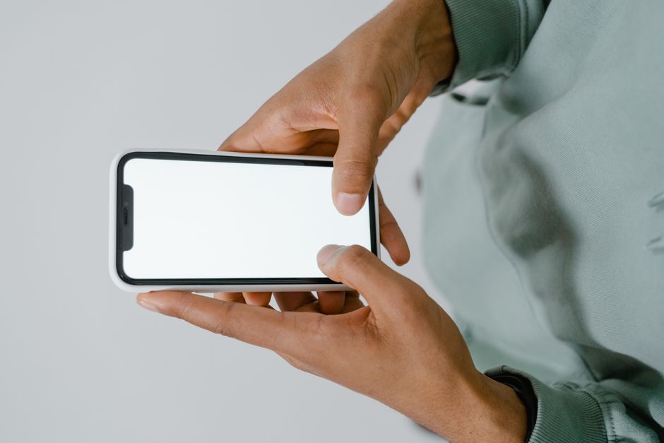 Hands holding a smartphone with a blank screen, perfect for mockups or copy space.