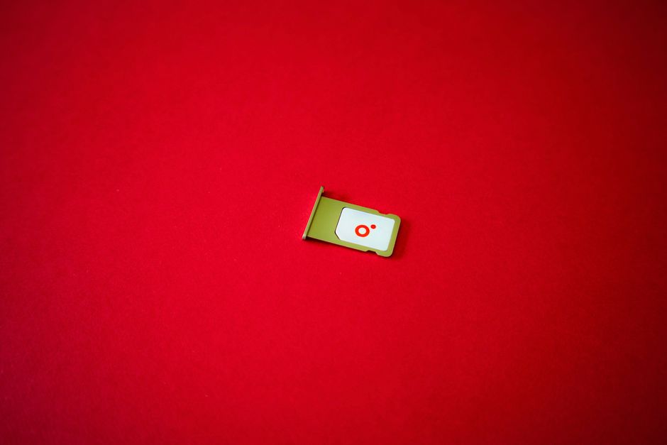 A clean image of a SIM card tray displayed on a vibrant red background.